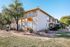 Charming two-story apartment building with beautiful trees and well-maintained landscaping under a clear blue sky.