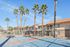Sunny apartment complex with vibrant palm trees and a welcoming basketball court under a clear blue sky.