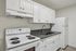 Modern kitchen with sleek white cabinetry, black countertops, and stainless steel fixtures, perfect for culinary creativity.