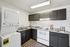 Modern kitchen with sleek dark cabinets, a contemporary electric stove, and in-unit washer and dryer, perfect for a convenient lifestyle.