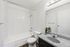 Contemporary bathroom with elegant gray speckled countertop, sleek fixtures, and a cozy bathtub featuring white tiling.