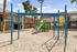 Inviting apartment playground with vibrant blue and green slides, climbing structures, and beautiful palm trees.