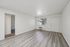Bright living area with modern wood flooring, large window for natural light, and a doorway leading to additional rooms.