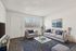 Bright and modern living room with stylish gray couches, elegant decor, and a large window offering abundant natural light.