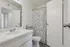 Bright and inviting bathroom featuring floral shower curtain, sleek white countertop, and modern fixtures.