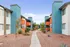 Vibrant apartment community showcasing modern architecture with bold blue and orange facades, complemented by a beautifully landscaped walkway.