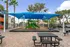 Inviting outdoor playground with vibrant slides under a blue shade, surrounded by lush greenery and seating areas.
