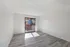 Bright and airy living room featuring sleek hardwood floors and large sliding glass doors opening to a cozy balcony.
