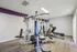 Modern fitness room equipped with premium exercise machines on sleek wooden flooring, highlighted by a stylish purple accent wall.