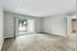 Spacious living room with elegant wood flooring, large sliding glass doors opening to a serene outdoor view, perfect for natural light and modern living.