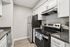 Modern kitchen with sleek stainless steel appliances, elegant white cabinetry, and spacious countertops complemented by wood-look flooring.