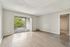 Bright and airy living space with sleek wood flooring and large sliding glass doors opening to a scenic balcony view.
