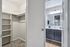Elegant apartment with a spacious walk-in closet featuring built-in shelving, alongside a modern bathroom with sleek fixtures and ample lighting.