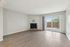 Bright, spacious living room with elegant fireplace and large glass doors leading to a sunny patio.