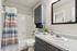 Bright, modern bathroom with sleek granite countertop, stylish dark cabinetry, and a vibrant striped shower curtain.
