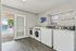 Modern apartment laundry room with sleek washers and dryers, featuring elegant flooring and a view of a sparkling pool through French doors.