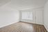 Bright, modern living room with sleek wooden floors and ample natural light through large window.