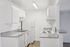 Bright contemporary kitchen with sleek white cabinets, modern gray countertops, and stainless steel appliances.