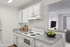 Bright, modern kitchen with sleek white cabinets, granite countertops, and an inviting open layout overlooking a cozy living room.