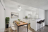 Chic and modern dining area with elegant artwork, sleek white cabinets, and a cozy breakfast bar with high stools.