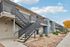Modern apartment complex with sleek balconies and easy-access stairways, surrounded by well-maintained landscaping under a bright blue sky.