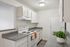 Modern kitchen with sleek countertops, built-in stove, and bright white cabinetry, enhanced by a touch of greenery for a vibrant feel.