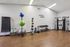 Modern apartment gym with exercise balls, weights, and strength machines on wooden floors. Energizing space with motivational quote.