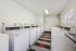 Modern laundry room equipped with multiple washers, featuring a sleek black and red checkered floor design.