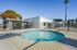 Inviting apartment complex with a sparkling spa in a sunny, private fenced area and lush greenery, perfect for relaxation.