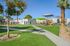 Vibrant residential playground featuring modern play structures and lush green landscaping under a clear blue sky.