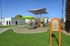 Charming playground with vibrant slides and climbing structures, set amidst lush green grass and modern architecture, perfect for family fun.