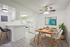 Elegant kitchen and dining area with cozy white decor, modern appliances, vibrant artwork, and a welcoming atmosphere.
