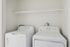 Contemporary laundry setup featuring a sleek washer and dryer with ample overhead shelving for convenience.