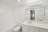 Bright and modern bathroom featuring a sleek vanity mirror, elegant countertop, and inviting bathtub, exuding a fresh and clean ambiance.