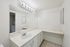 Elegant bathroom with pristine white vanity, expansive mirror, and chic lighting, offering a refreshing and modern atmosphere.