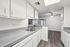 Bright and inviting kitchen with sleek white cabinetry, modern countertops, and an open view to the dining area, enhanced by natural light.
