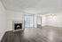 Bright and spacious living room with elegant wooden flooring, cozy fireplace, ceiling fan, and large sliding glass door leading to a private balcony, perfect for modern living.