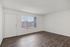 Bright and inviting empty room with elegant wood flooring and large window, perfect for customizable living space.