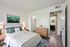 Beautifully staged bedroom featuring a plush bed with green accents, modern wooden furniture, and an inviting ambiance. Adjoining bathroom adds convenience and luxury.