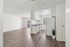 Bright, open-concept kitchen and living area with sleek hardwood flooring and modern white cabinetry, leading to a sunny balcony.
