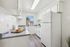 Bright, modern kitchen with sleek countertops, white cabinetry, and natural light streaming through a window.