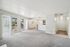 Bright and spacious apartment living area with large windows, plush carpeting, modern kitchen, and balcony access.