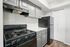 Modern kitchen featuring sleek black appliances, elegant gray cabinetry, and polished white countertops for a stylish cooking space.