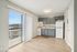 Modern kitchen with sleek gray cabinetry, natural light from a large balcony window, perfect blend of style and functionality.