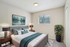 Modern and inviting bedroom with plush bedding, elegant decor, and ample natural light from a large window. Features stylish artwork and contemporary furnishings in a virtually staged setup.
