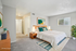 Brightly lit bedroom with modern decor, plush carpeting, and inviting king-size bed, accentuated by a stylish rug and large window for ample natural light.