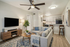 Chic modern living room with cozy gray sofa, elegant wooden furniture, and an open kitchen featuring bar stools, perfect for stylish apartment living.