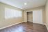 Bright, modern bedroom with laminate flooring, large window with vertical blinds, and a spacious closet.