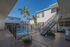 Inviting apartment courtyard featuring a refreshing pool, surrounded by lush palm trees and modern architecture.