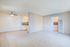 Bright living area with modern ceiling fan, adjacent to a sleek kitchen featuring tiled backsplash and neutral tiled flooring.